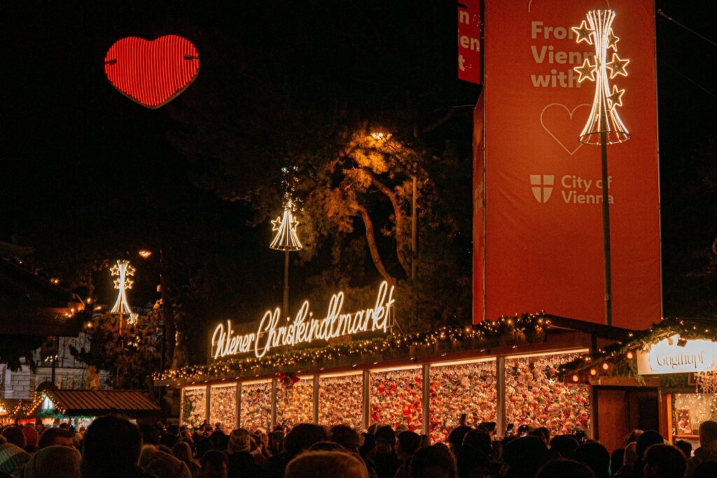 Christmas market stalls with a banner of Vienna in the background