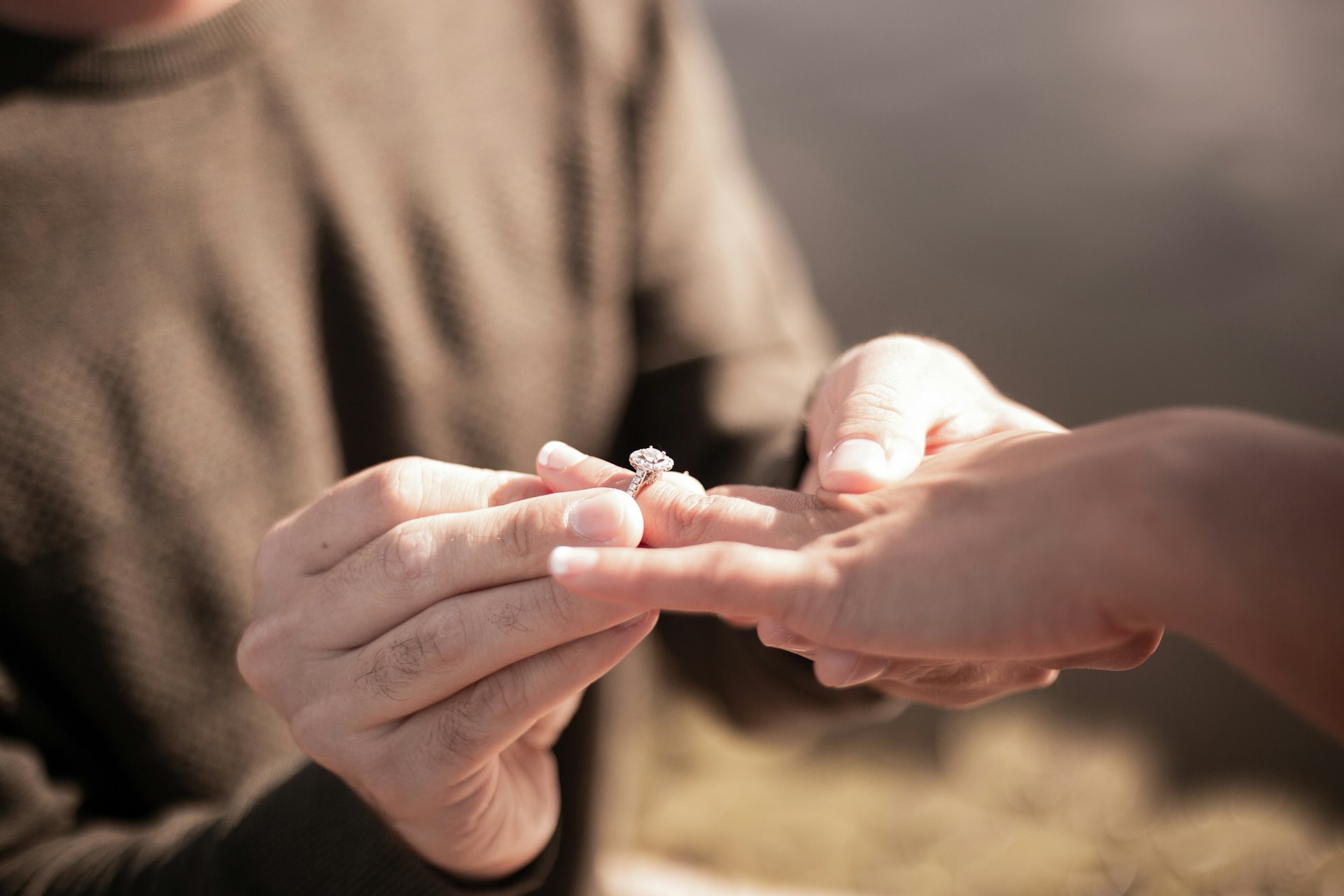 A couple putting on an engagement ring